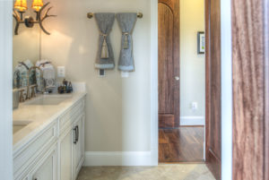 A custom bathroom with a brown door, white granite sink, and moody lighting.
