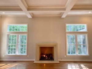 Living room with white walls, two large windows, and a fireplace.