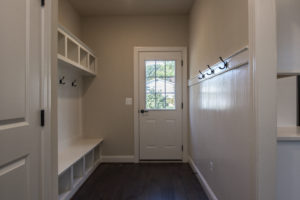 White walls and built-in storage with a back door and dark brown flooring.