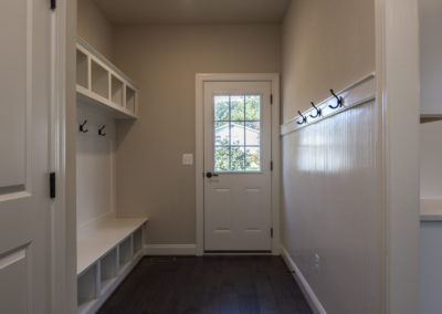 White walls and built-in storage with a back door and dark brown flooring.