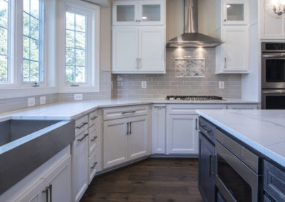 White kitchen counters and tan backsplash with stove and oven.