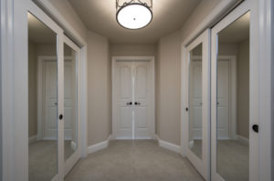 White carpet, walls, and doors with large sliding closet doors with mirrors attached.
